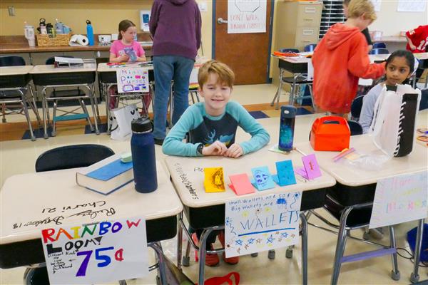 boy smiling at desk with colorful paper wallets
